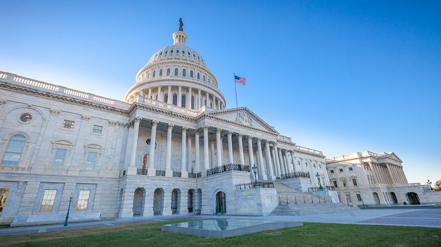 The United States Capitol Building in Washington, D.C. stands against a bright, clear blue sky.