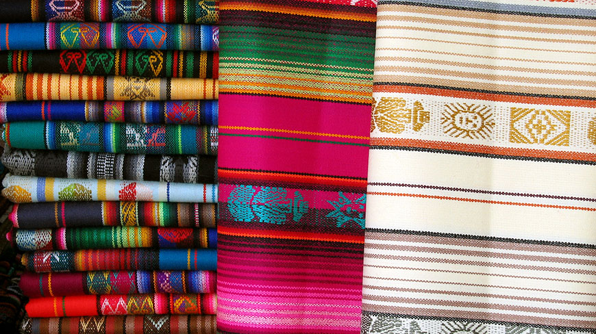 A close-up of colorful, hand-woven Otavalo blankets with traditional patterns from Ecuador.