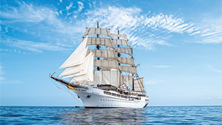 The tall ship Sea Cloud II sailing on the Adriatic Sea between Italy and Croatia under a blue, partly cloudy sky.
