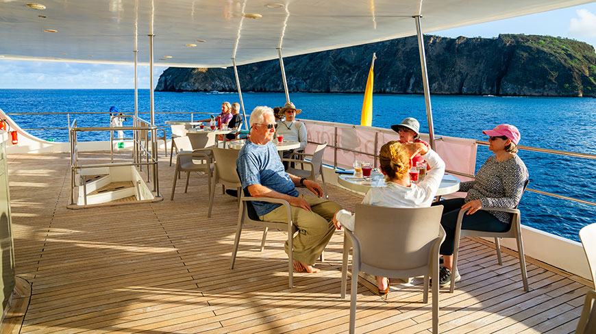 A group of travelers relax on the sundeck of a ship cruising through the Galápagos Islands, Ecuador.