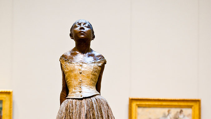A bronze sculpture by Degas of a young dancer with her head tilted back, on display at the Metropolitan Museum of Modern Art.