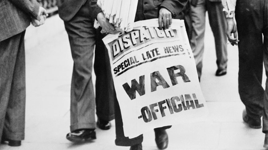A person holds a newspaper with the headline "WAR - OFFICIAL" in the United Kingdom during World War II.