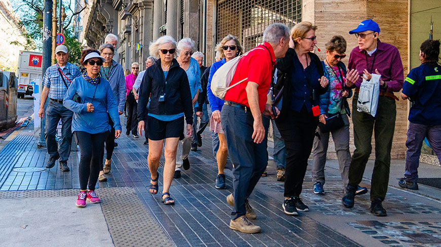 A group of older adults participates in a walking tour on a city sidewalk in Washington, D.C.