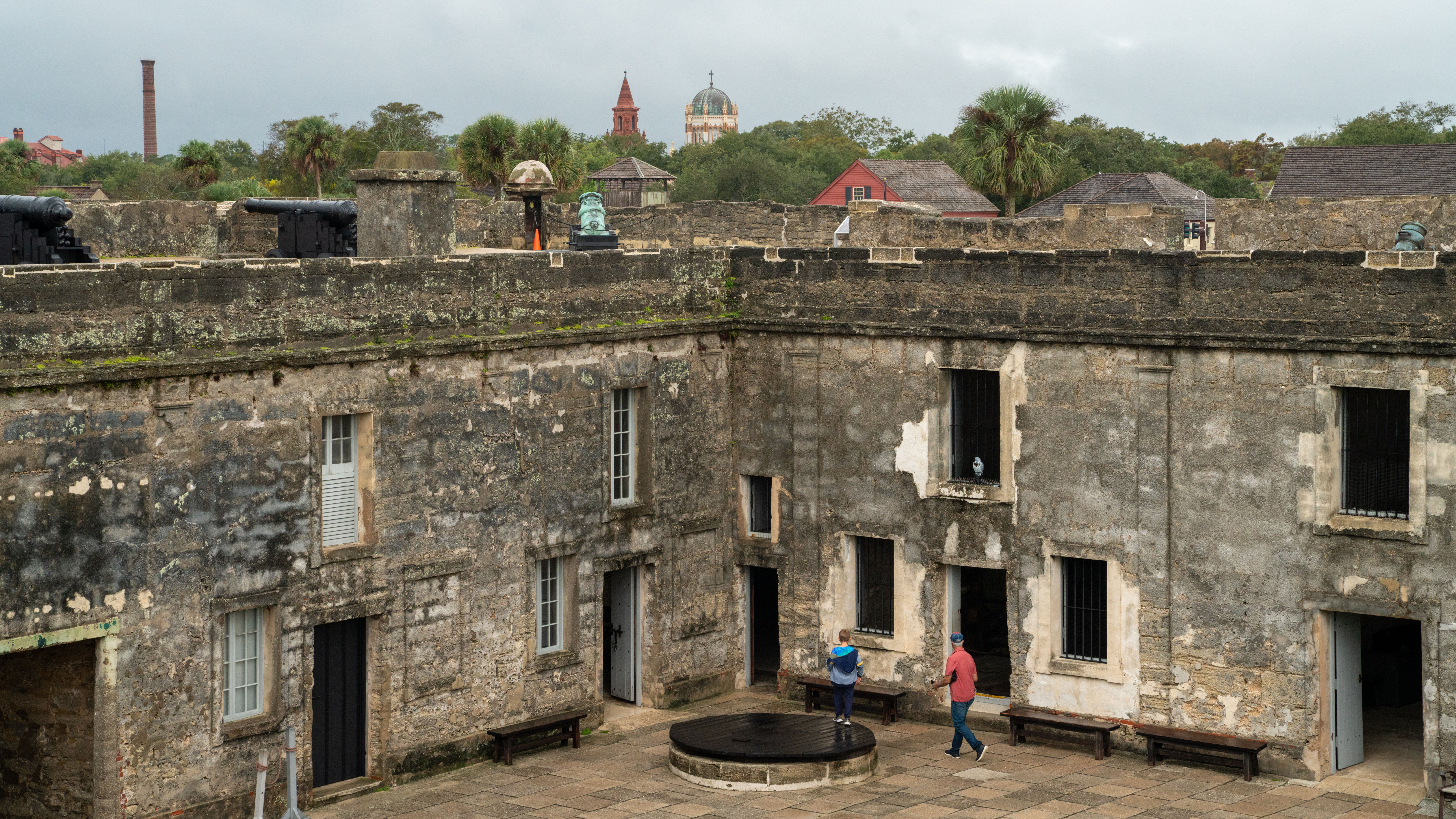 An elevated view of the stone courtyard of the Castillo de San Marcos in St. Augustine, Florida, with cannons on the ramparts above.