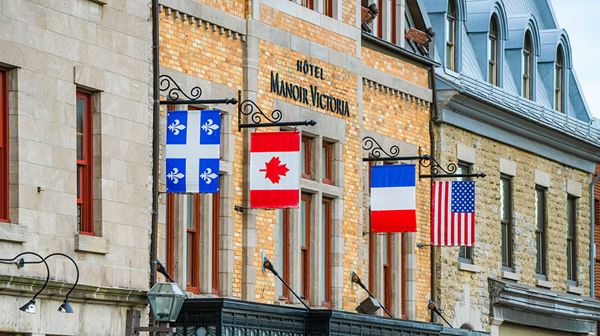 Flags of Quebec, Canada, France, and the USA hang outside the Hôtel Manoir Victoria in Old Quebec City, Canada.