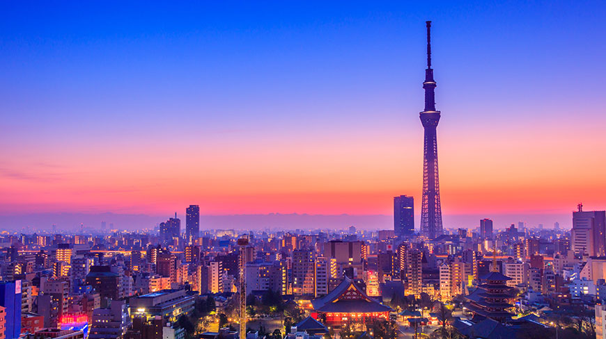 The Tokyo, Japan skyline and Skytree tower are illuminated by a colorful sunset and city lights.